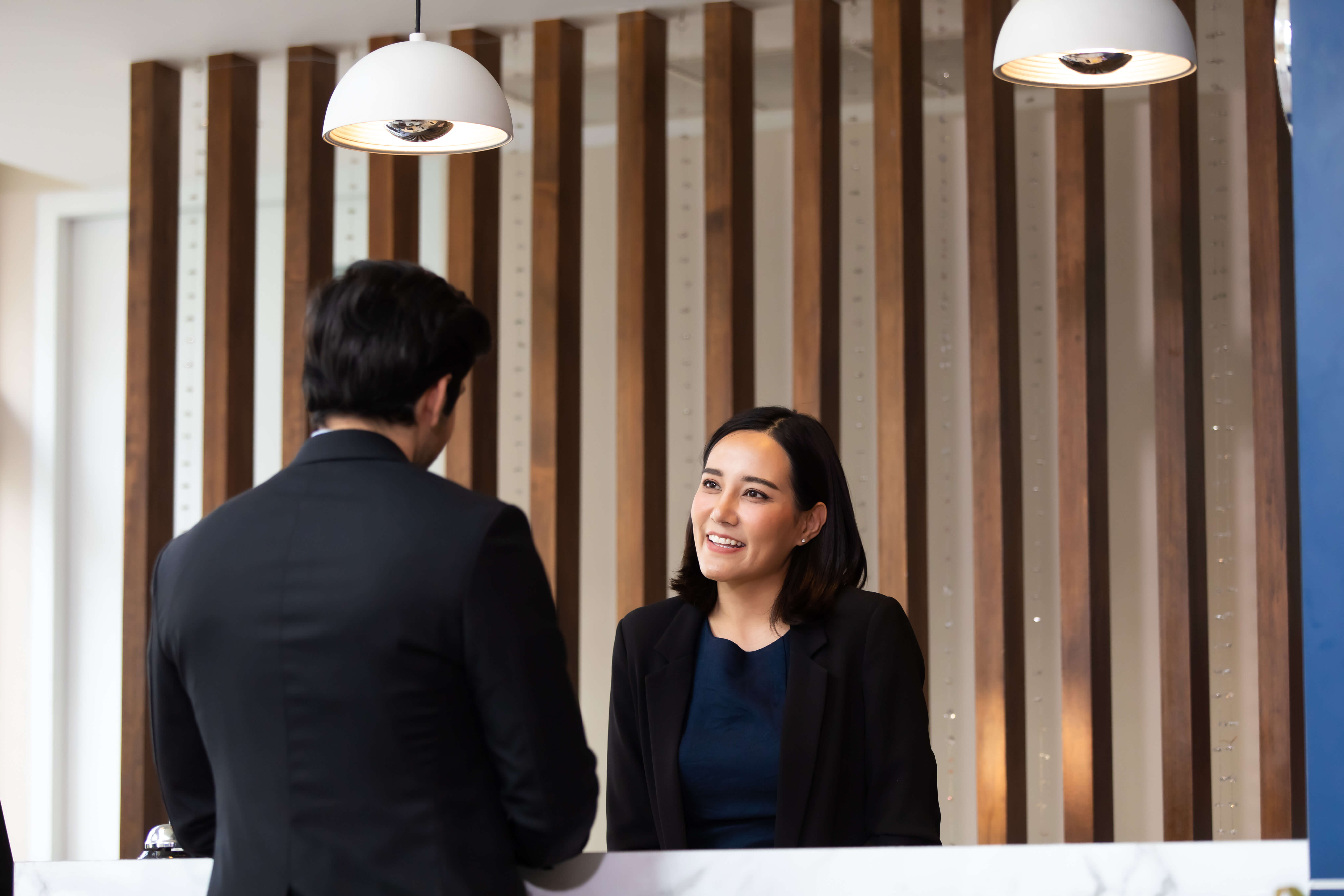 Amable mujer recepcionista trabajando en el mostrador del vestíbulo de un hotel. Ocio y viajes en vacaciones.